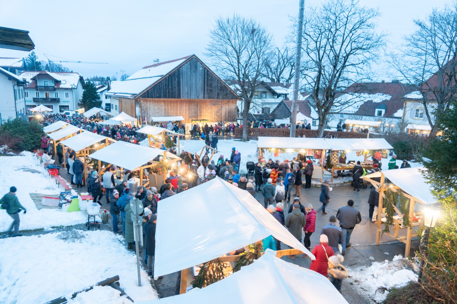 Winterlicher Christkindlmarkt in Bad Kohlgrub mit schneebedeckter Scheune und Marktständen