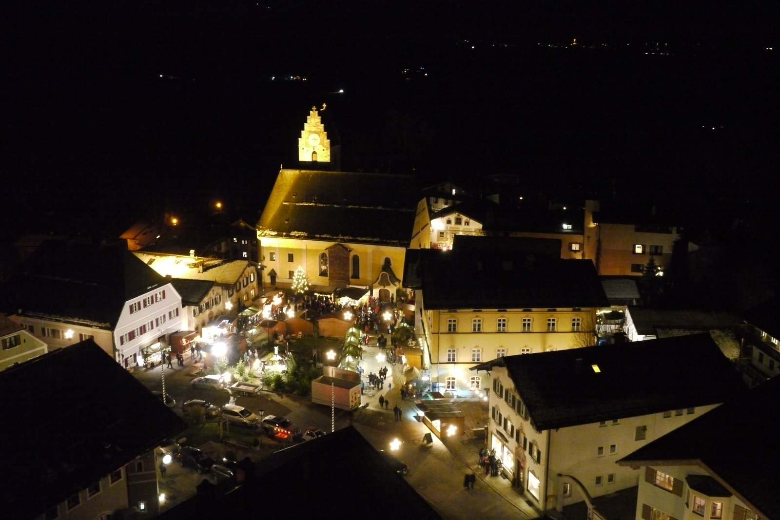 Neubeurer Christkindlmarkt bei Nacht: Luftaufnahme der beleuchteten Kirche und Marktstände im Ortskern