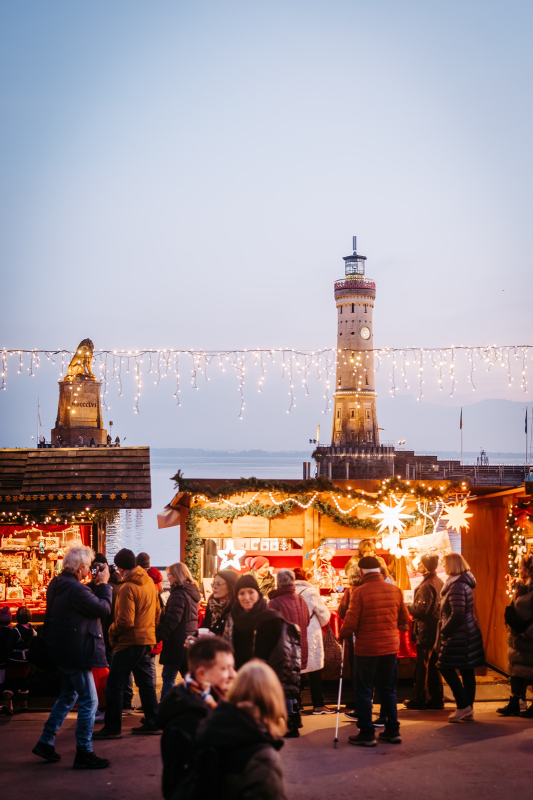 Lindauer Hafenweihnacht: der historische Leuchtturm im Bodensee-Hafen, geschmückt mit Lichterketten