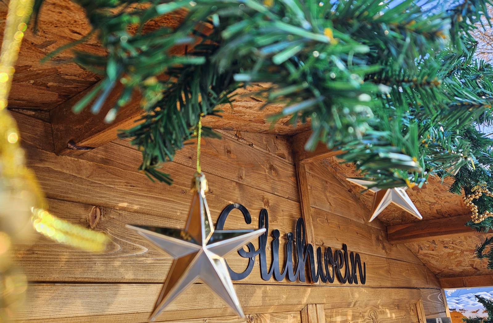 Glühwein-Schriftzug und Sterndekoration an einer Holzhütte auf dem Wintermarkt Reit im Winkl
