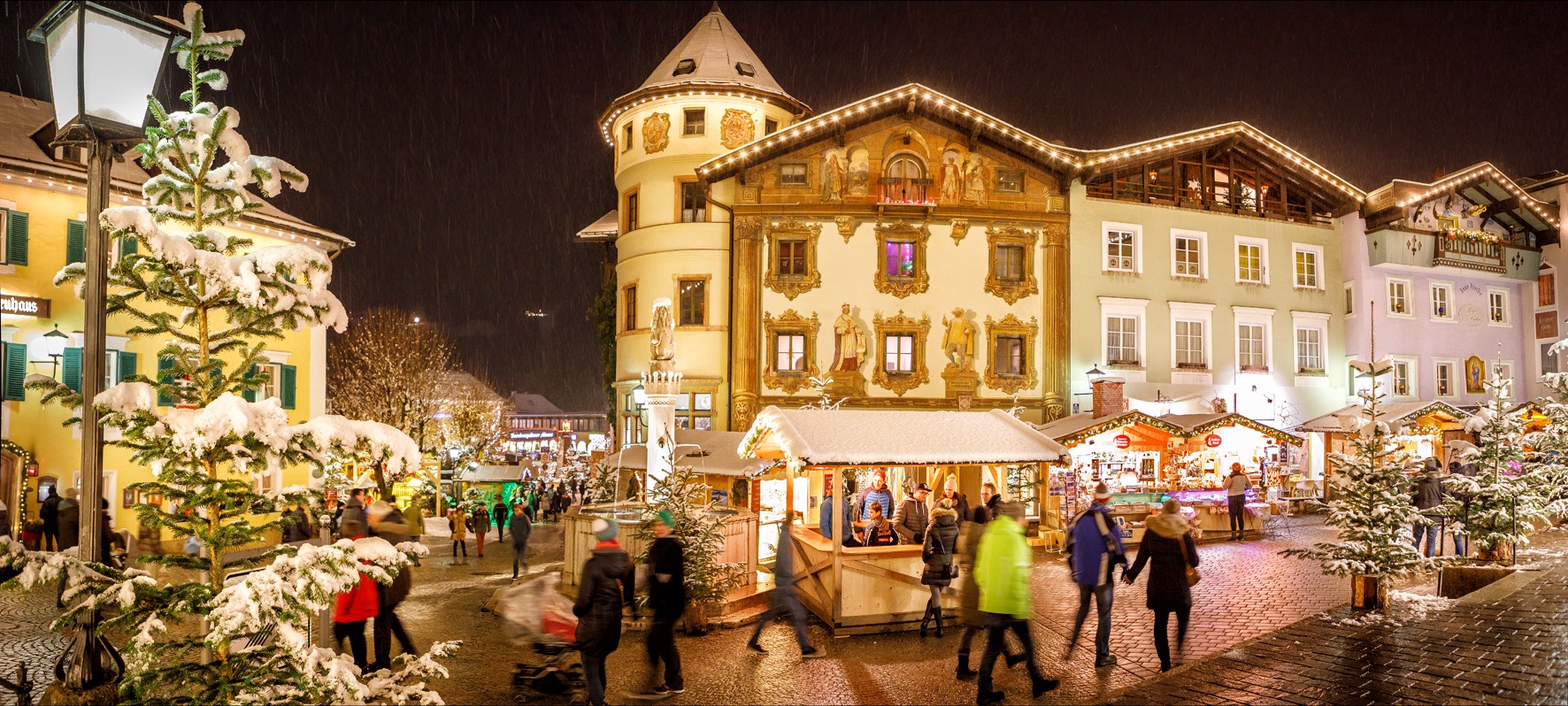 Berchtesgadener Advent am verschneiten Marktplatz, beleuchtete Marktstände vor bemalten Fassaden