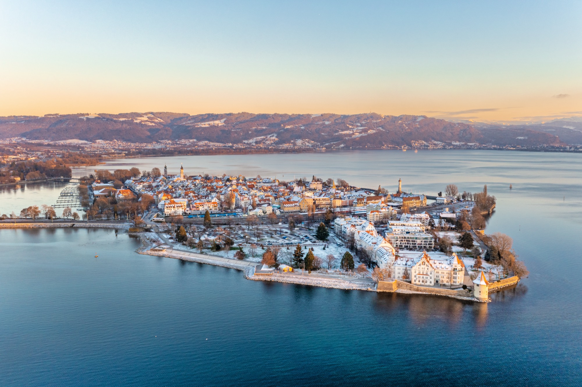 Lindauer Insel im Winter aus der Luft, verschneite Dächer und Hafen im Abendlicht über dem Bodensee