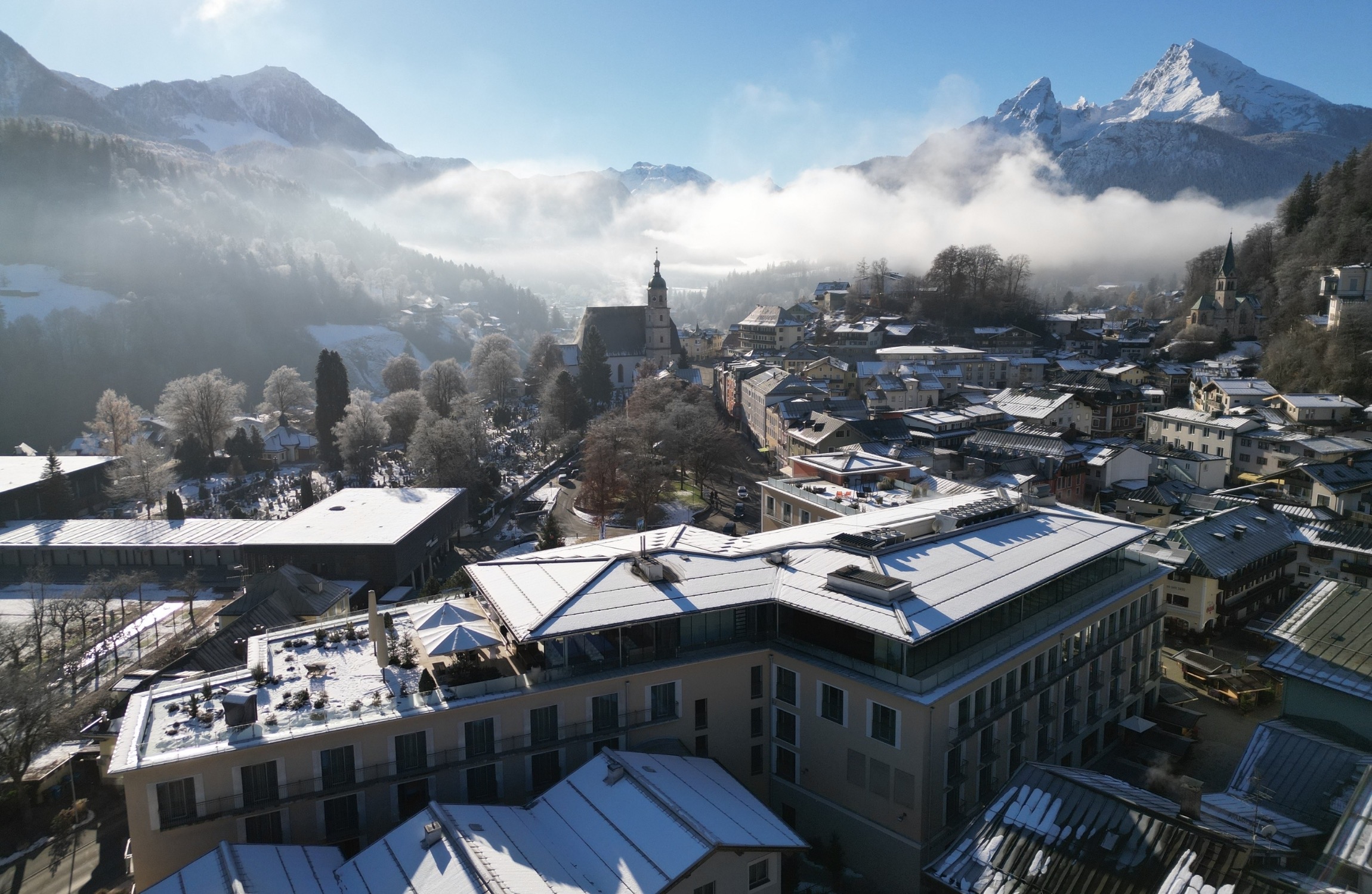 Hotel EDELWEISS im verschneiten Zentrum von Berchtesgaden aus der Luft, dahinter der Watzmann im Morgennebel
