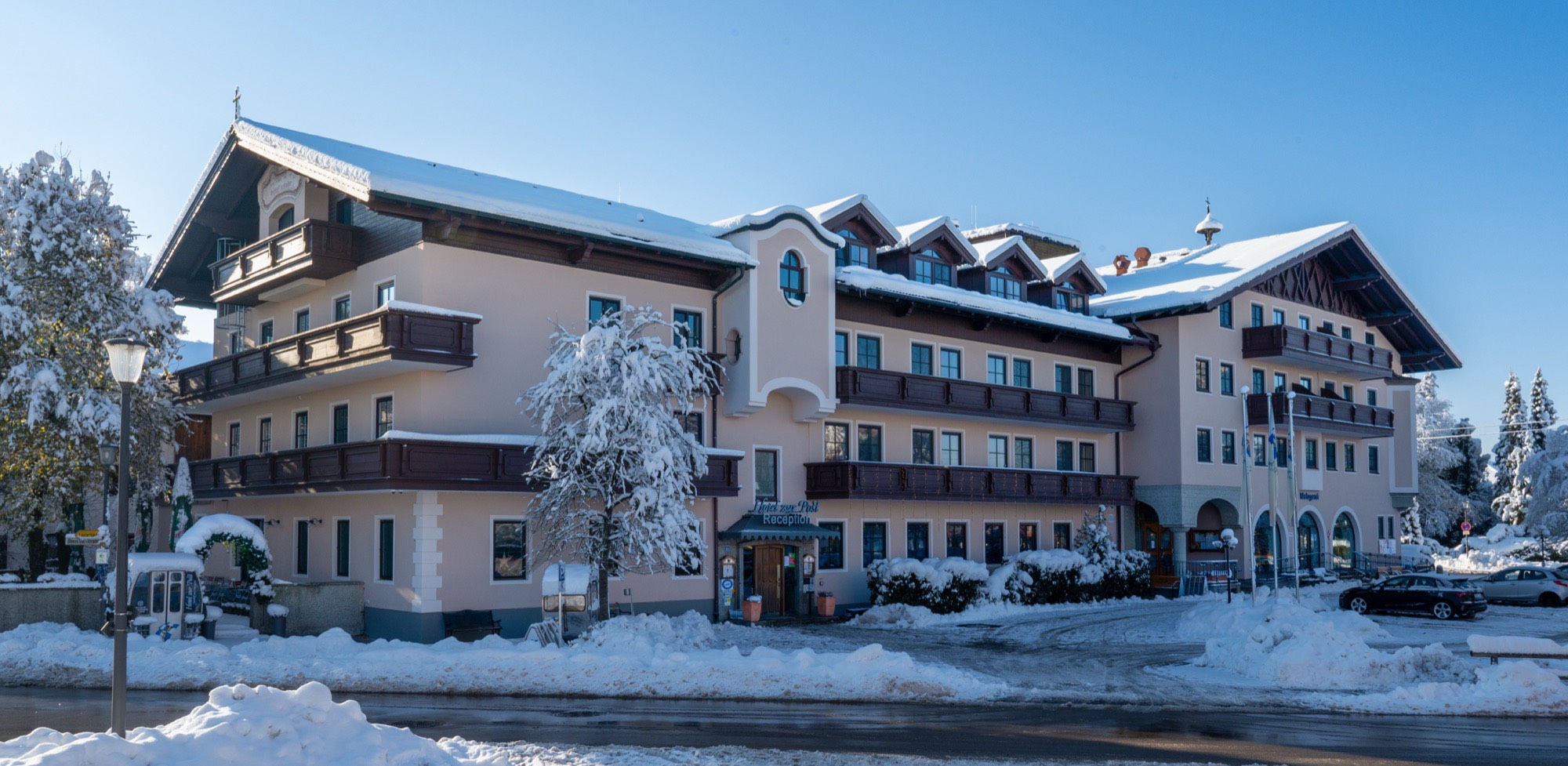 Hotel zur Post in Rohrdorf im Winter, verschneite Fassade mit Holzbalkonen unter blauem Himmel