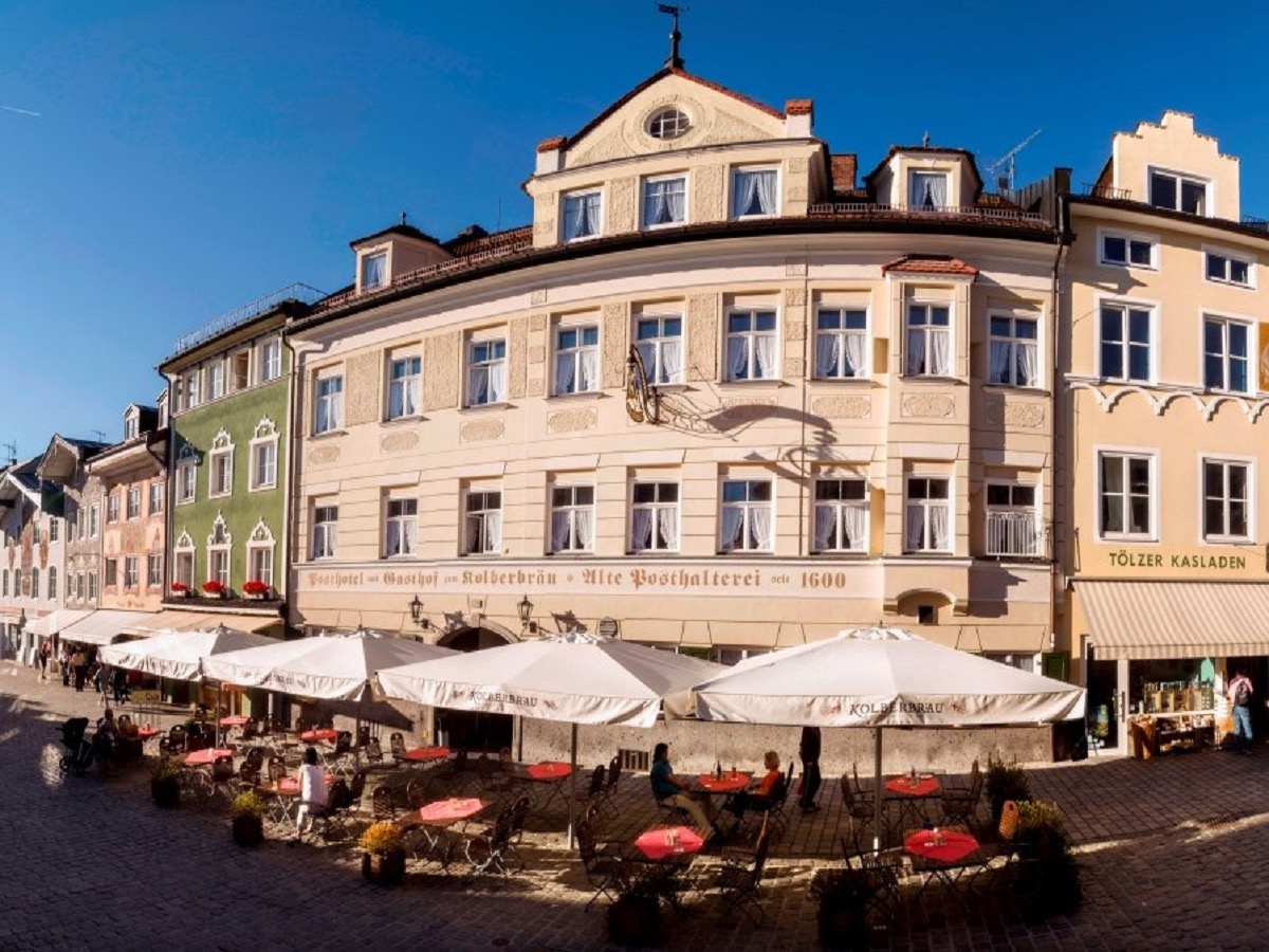 Posthotel Kolberbräu an der Tölzer Marktstraße, historische Fassade mit Biergarten-Schirmen bei Sonne